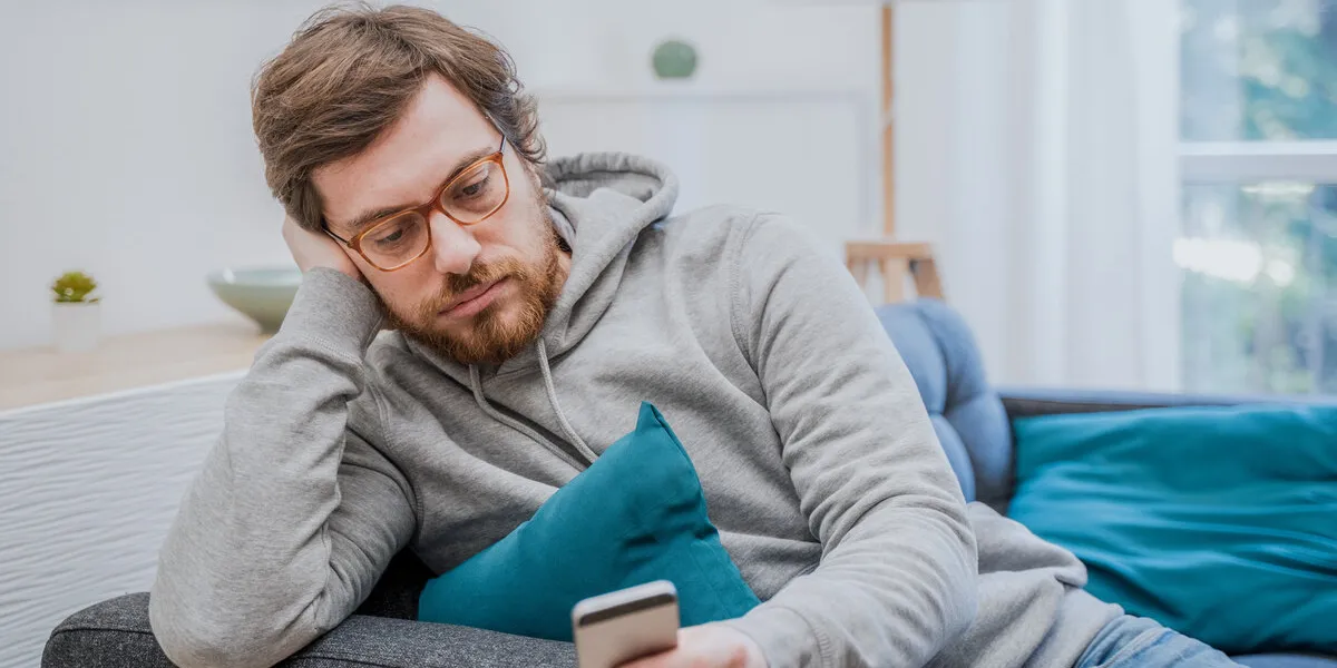 portrait of worried man on the sofa holding cellphone at home