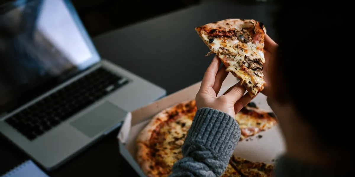 eating pizza and social networking with a laptop