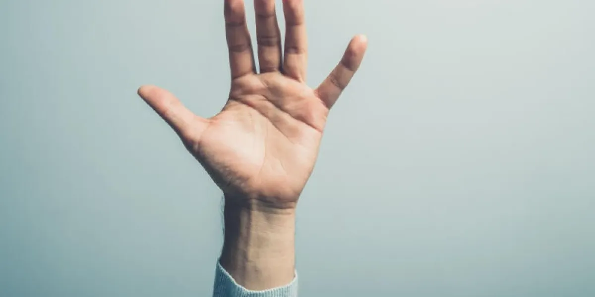 une main masculine agite devant un mur bleu