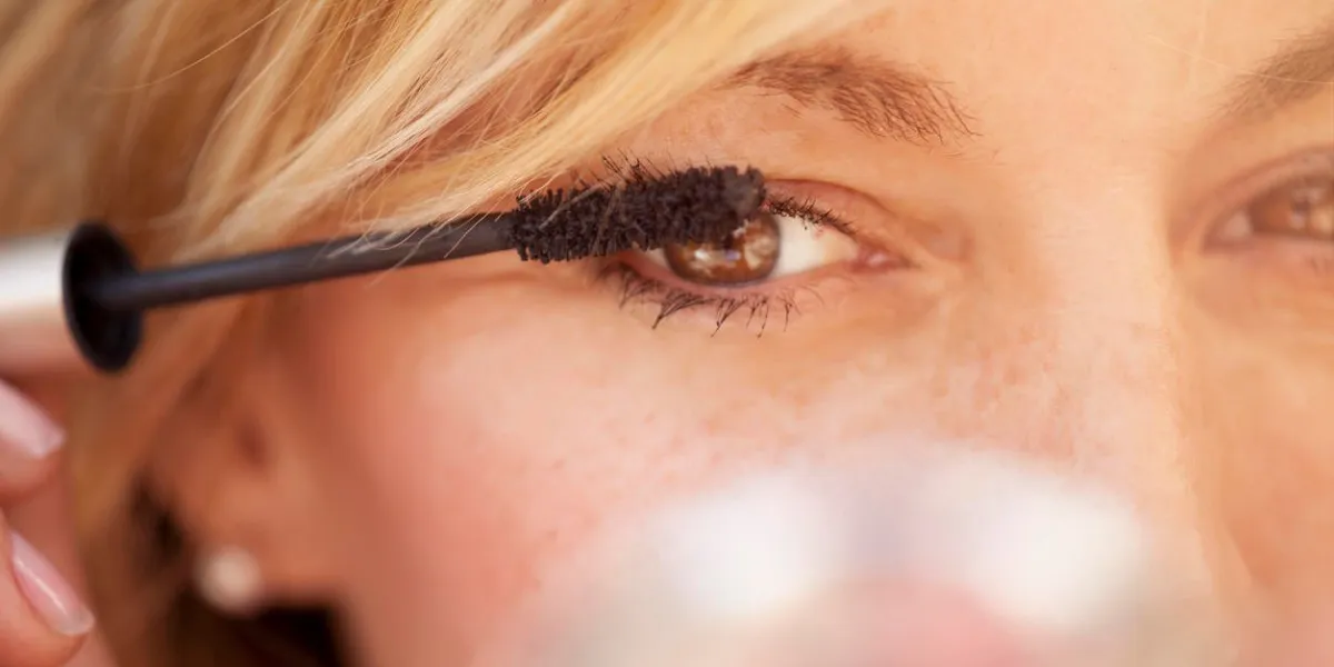 mignonne femme d'âge moyen mettant du mascara sur