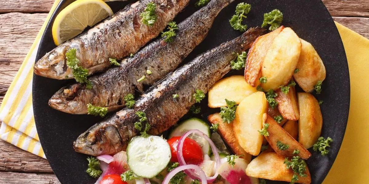 fried sardines with roasted potatoes and fresh salad closeup horizontal top view
