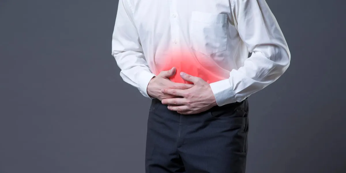 man with abdominal pain, stomach ache on gray background, studio shot with red spots