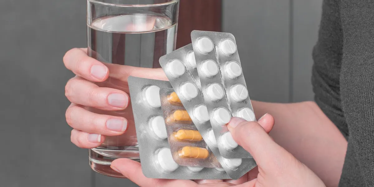 woman hands with pills and glass of water healthcare, medical concept