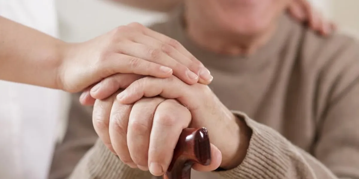 gros plan de main de soignant utile et vieil homme heureux