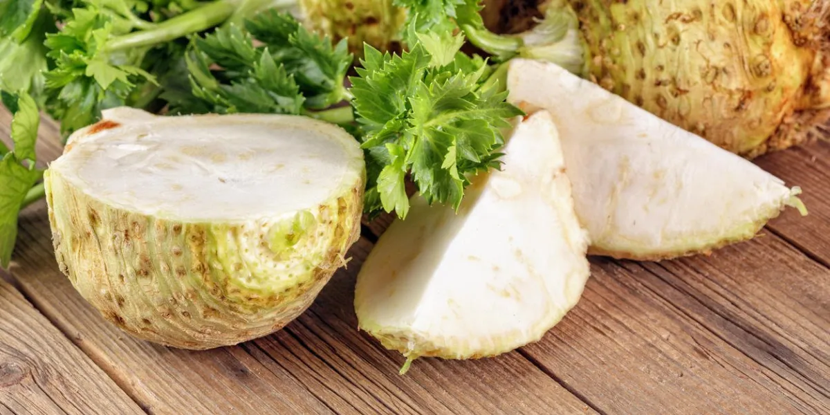 racine de céleri frais sur une planche de bois, une coupe