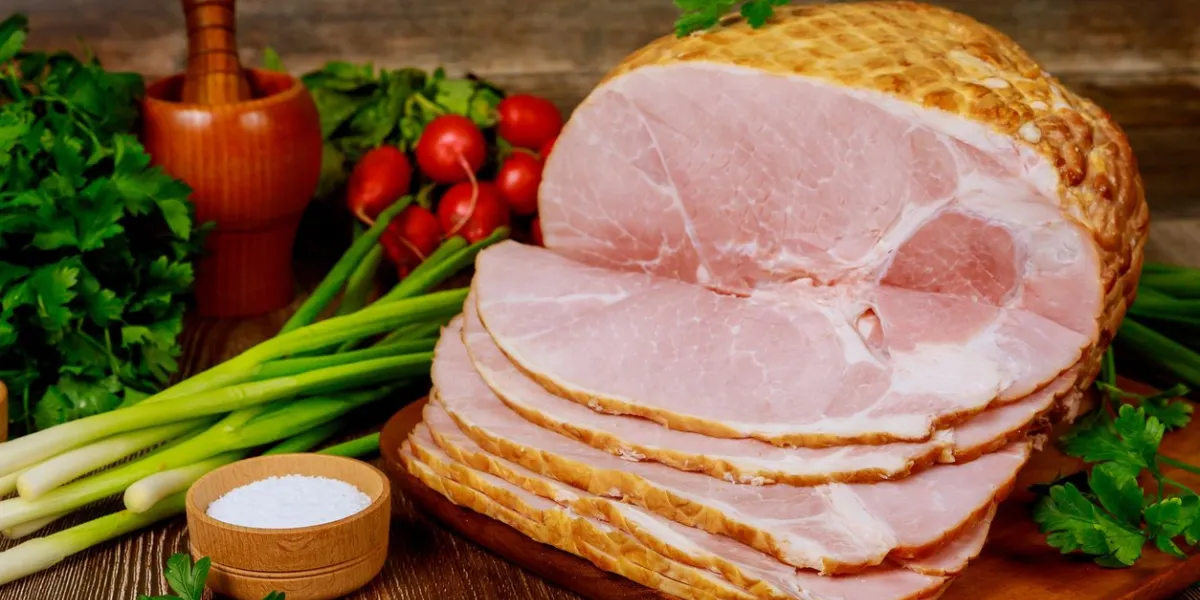 smoked boneless ham with vegetables and salt on wooden christmas table