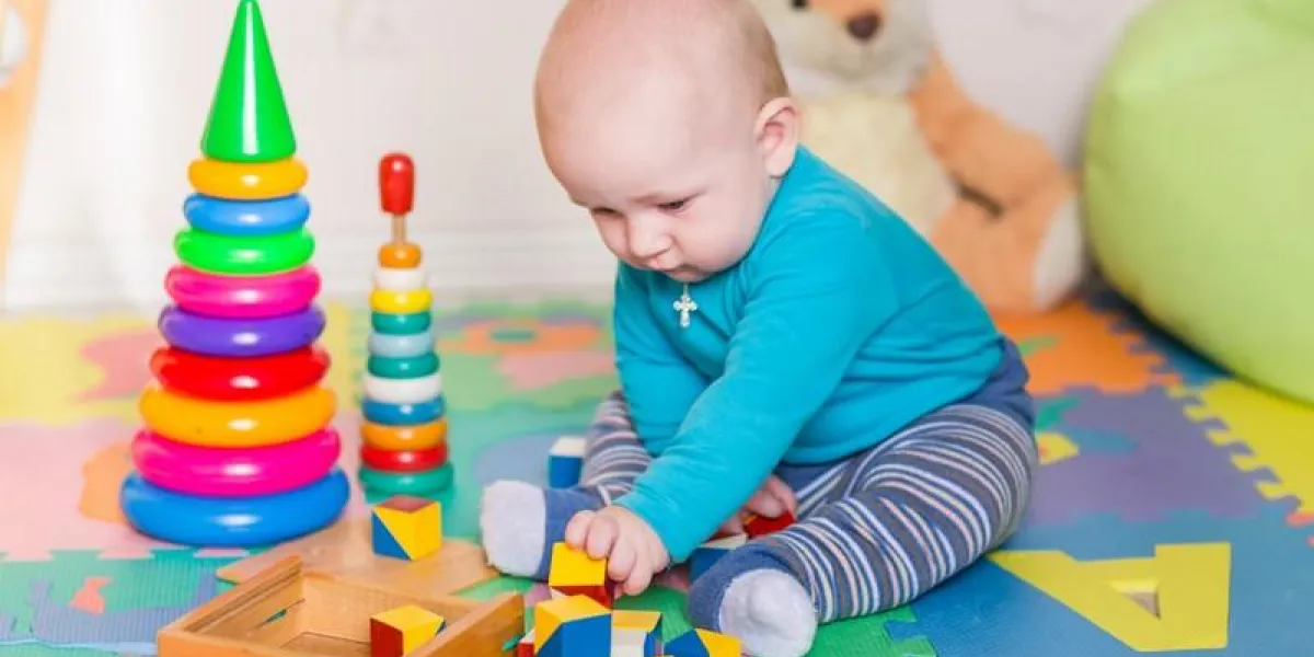 cute little baby playing with colorful toys at home
