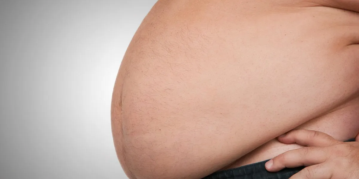 obesity, close up of fat mans belly, isolated on gray background with copy space