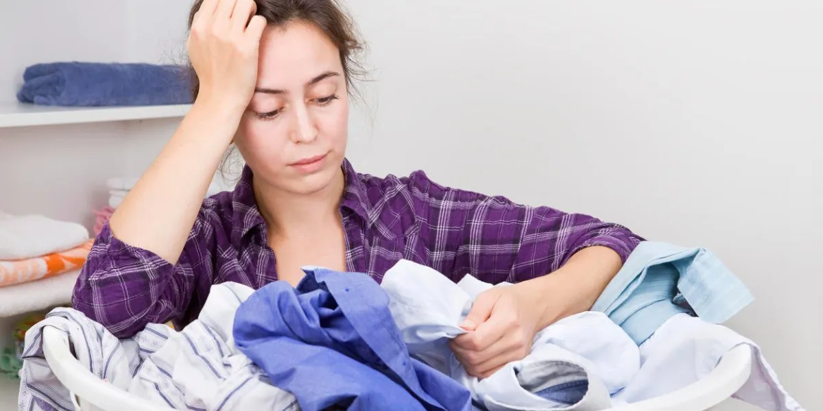 frustré jeune femme avec panier plein de vêtements