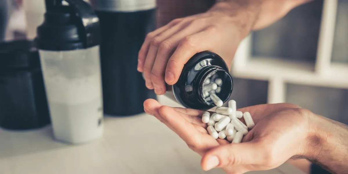 cropped image of handsome young sportsman preparing sport nutrition in kitchen at home