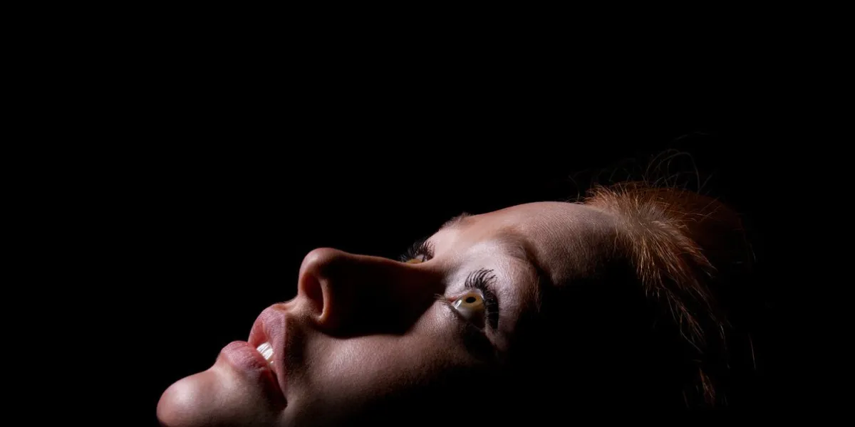 face of girl with red hairs looks up in dark