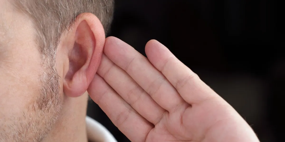 homme avec la main sur l'oreille à l'écoute pour le son calme ou en faisant attention