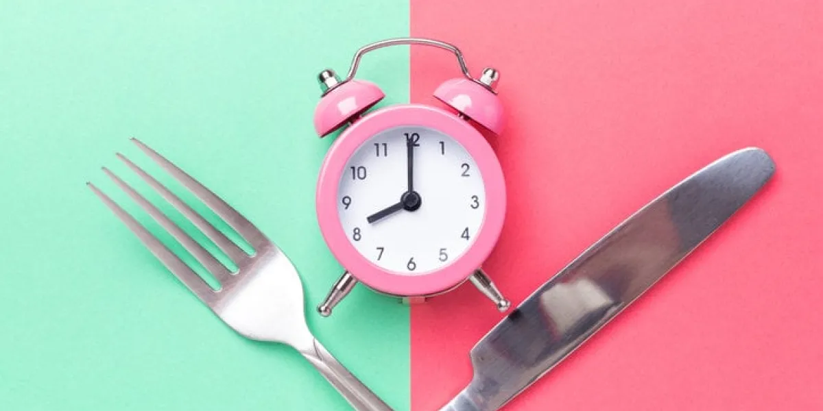 pink alarm clock, fork, knife on colored paper background intermittent fasting concept - image