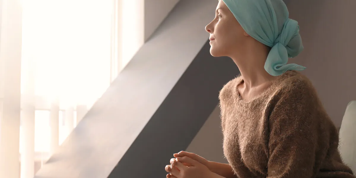 young woman with cancer in headscarf indoors