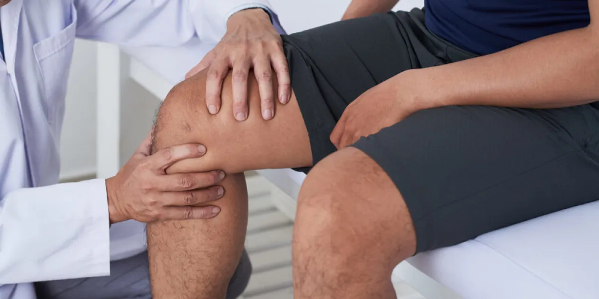 close-up image of doctor cheking knee of male patient
