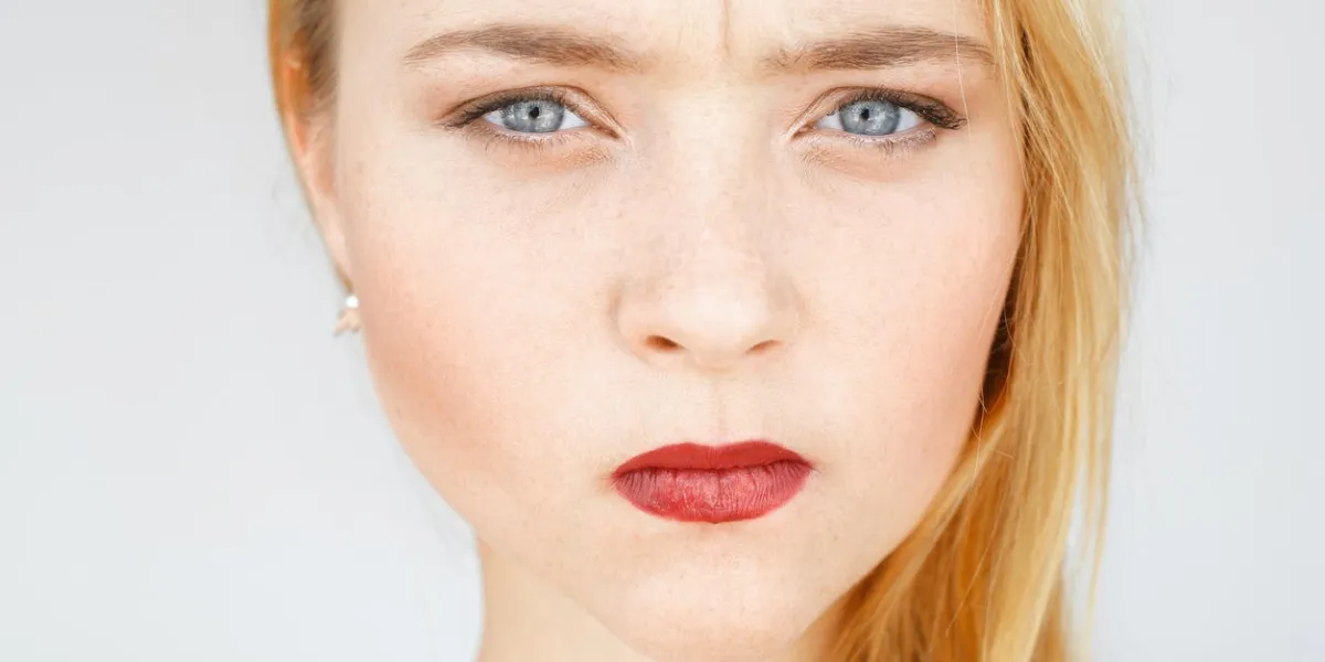 angry sad red-haired woman portrait young female with very serious and blaming look, pursed lips angry, frowning, grumpy carroty girl close-up