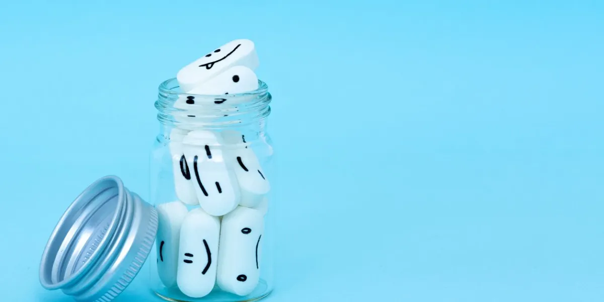 pills with funny faces and a glass bottle on a blue background pharmacy antibiotic treating with antidepressant mental disorder the concept of antidepressants and healing copy space