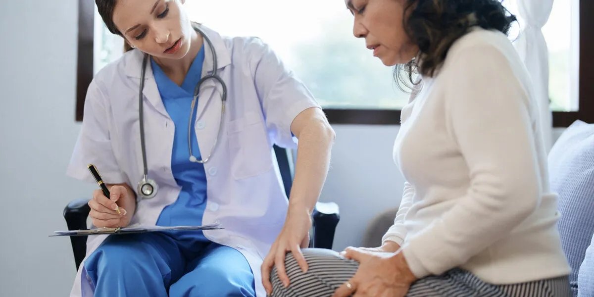 portrait of a female doctor talking to a patient with knee pain