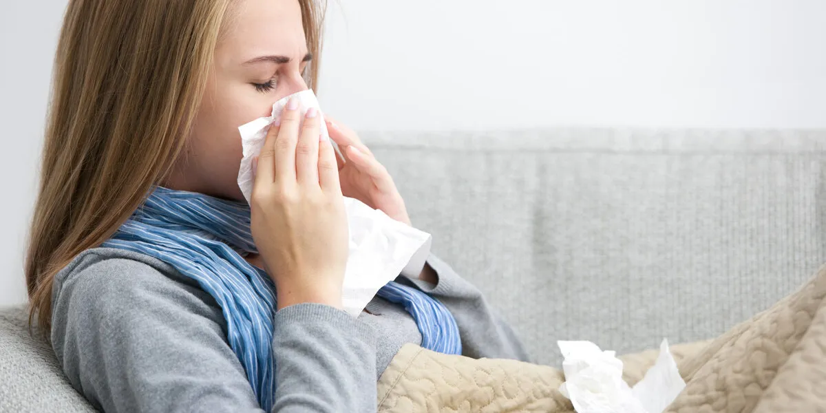 portrait of a young woman sneezing in to tissue
