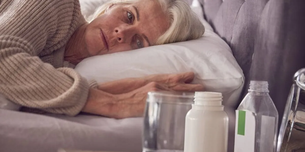 elderly woman, bed and medical addiction with pills, medicine or medication while lying awake at home senior female suffering from sick, illness or mental health, trauma or disorder in the bedroom