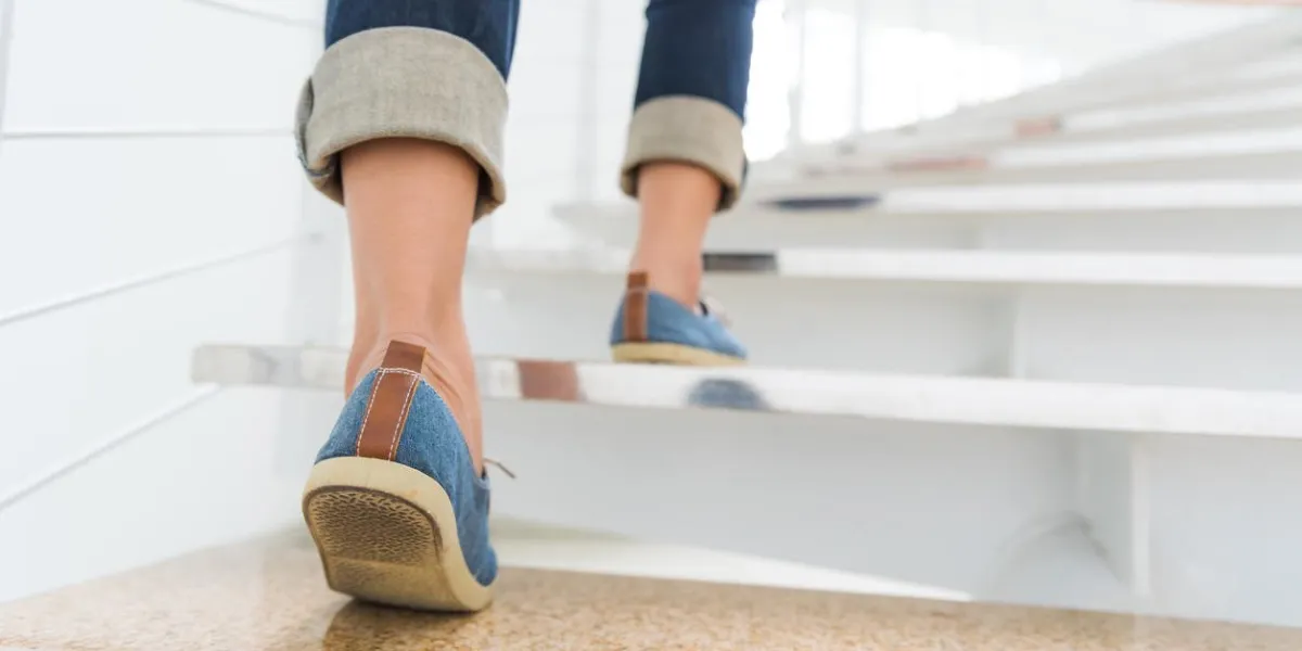 young adult woman walking up the stairs with sun sport background