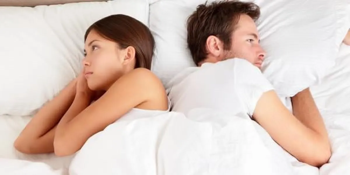 bouleversé jeune couple ayant des problèmes conjugaux ou un désaccord couché côte à côte dans le lit face à des directions opposées ignorant les uns les autres couple interracial, femme asiatique, homme caucasien