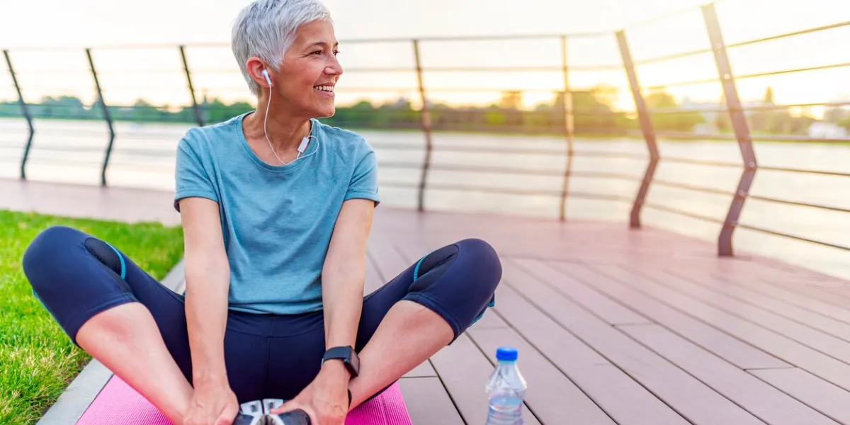senior woman exercising in park while listening to music senior woman doing her stretches outdoor athletic mature woman stretching after a good workout session