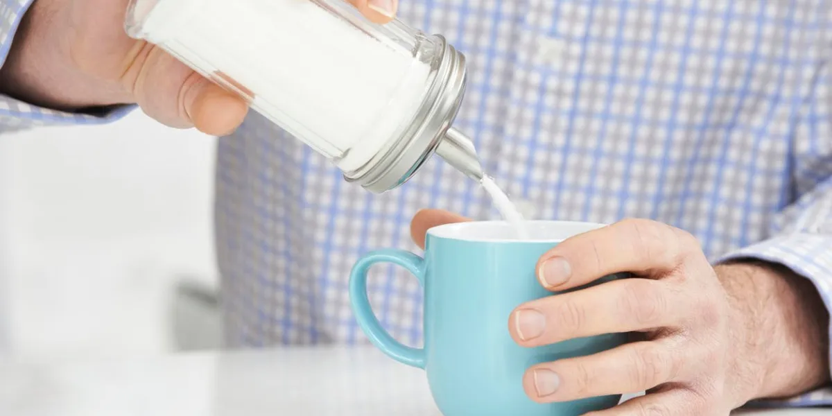 homme mûr, ajoutant du sucre à une tasse de café
