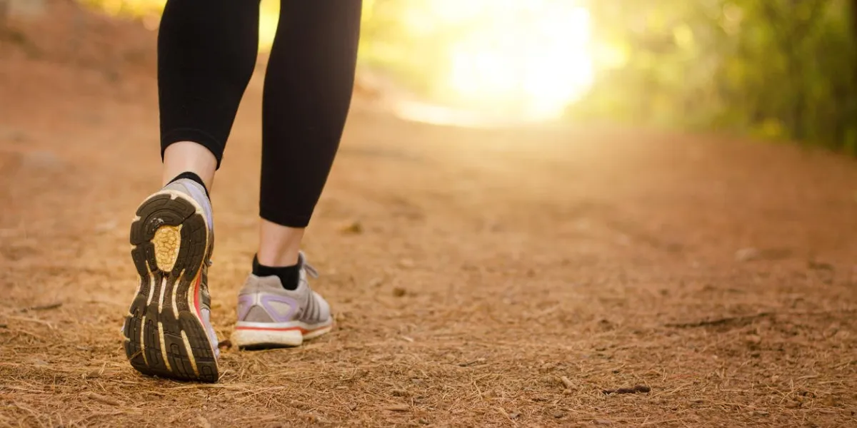 pair of legs walking on a trail in nature towards the light