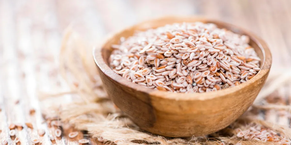 graines de psyllium dans un bol (gros plan) sur fond en bois