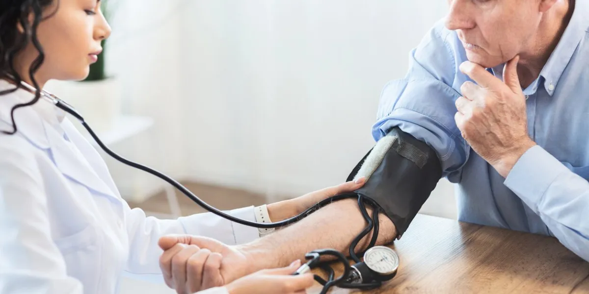 cardiology mexican doctor measuring blood pressure of senior man, checking patient, free space