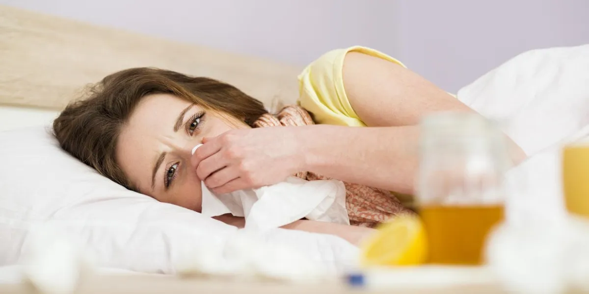 femme malade couchée dans son lit avec une forte fièvre, elle a le rhume et la grippe