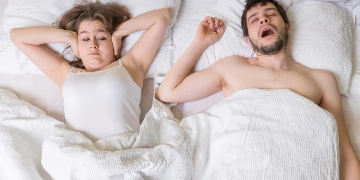 concept de ronflement jeune femme couvre ses oreilles l'homme ronfle dans son lit