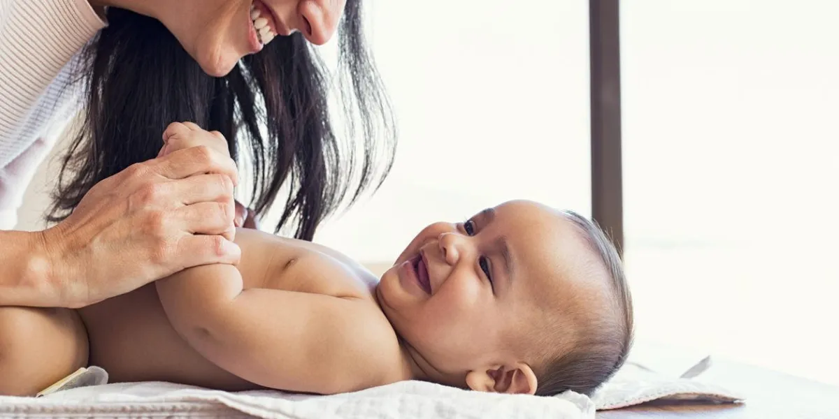 heureuse mère jouant avec bébé tout en changeant sa couche souriante jeune femme avec bébé fils sur la table à langer à la maison gros plan de joyeuse maman et enfant en bas âge jouant ensemble