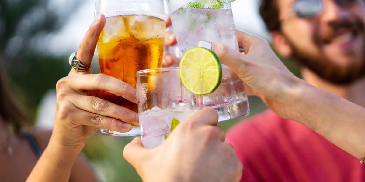 group of young friends toasting outdoors focus on glasses, blurred faces