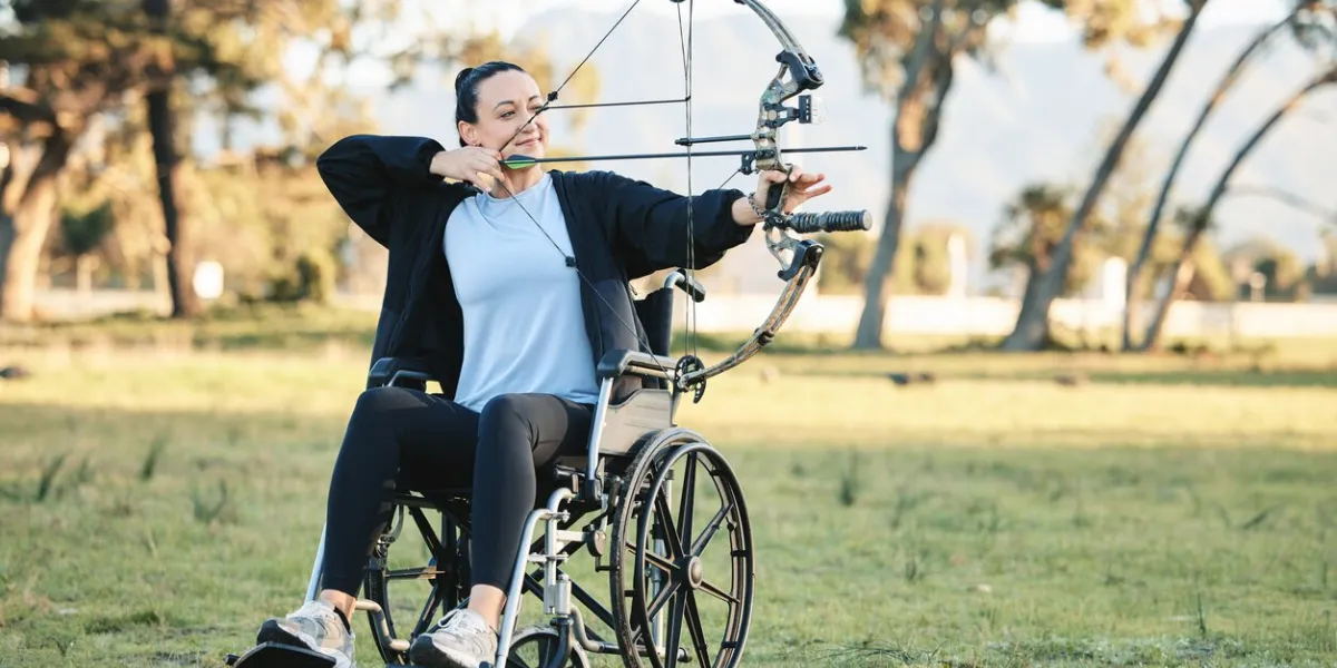disabled woman, outdoor archery in wheelchair and challenge with active sports lifestyle in canada person with disability in a park, fitness activity to exercise arms and aim arrow for hobby