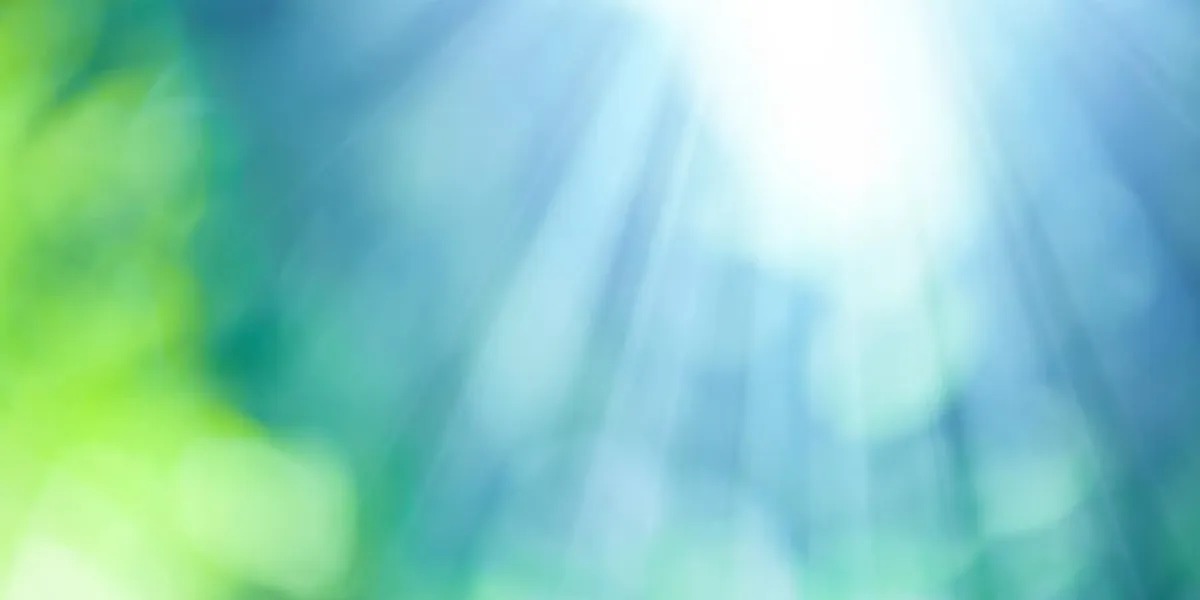 fond de bokeh naturel à l'extérieur dans les tons verts et bleus avec des rayons de soleil