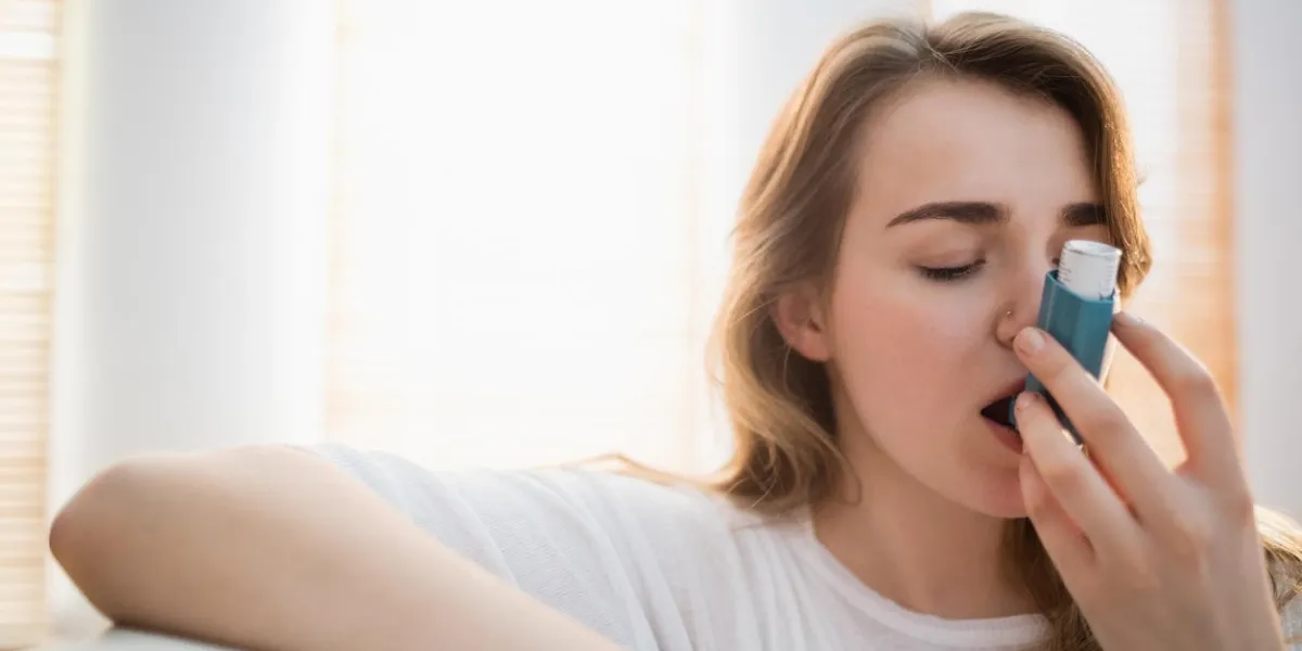 femme à l'aide de son inhalateur sur le canapé dans le salon