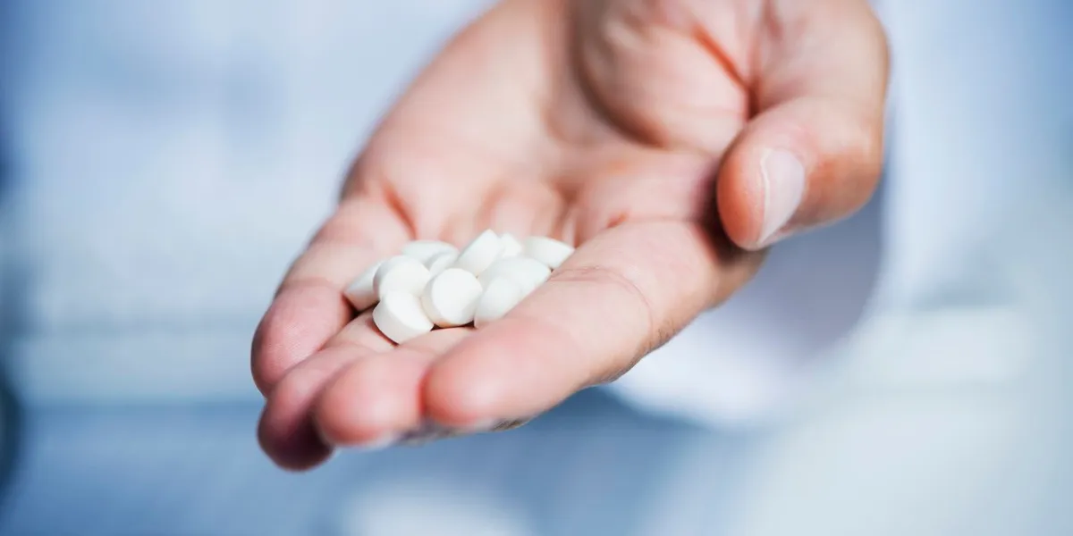 closeup of a caucasian doctor man, in a white coat, giving some pills to the observer