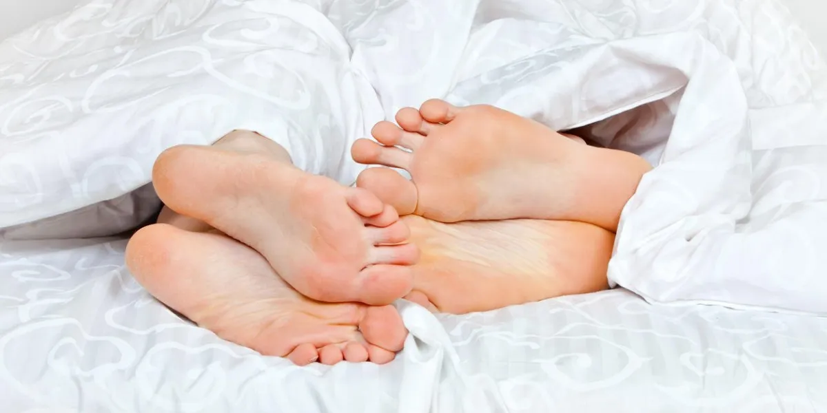 two sets of feet coming out of blankets in bed