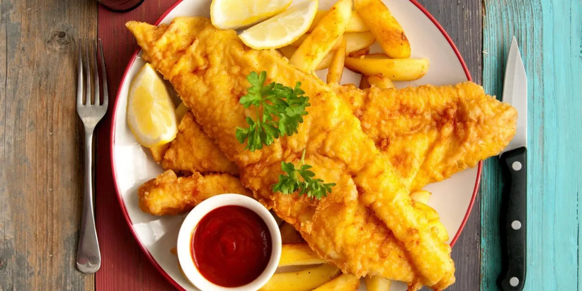 gros plan de deux morceaux de poisson pané sur une plaque avec des frites