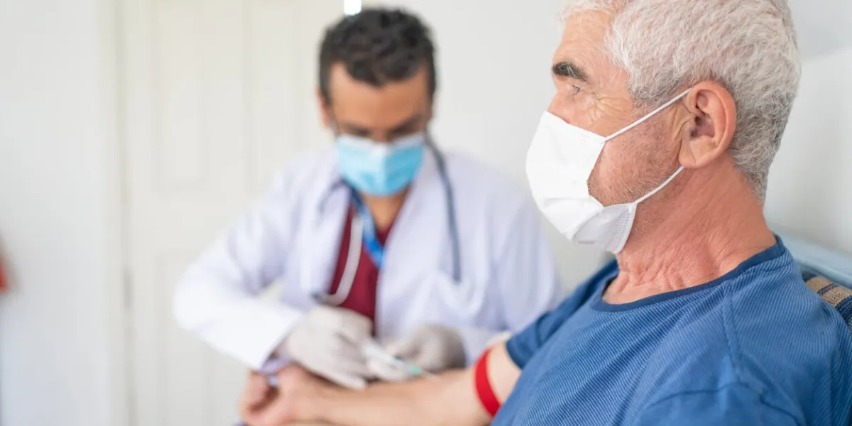 health worker is taking blood sample for analysis from old man in his house