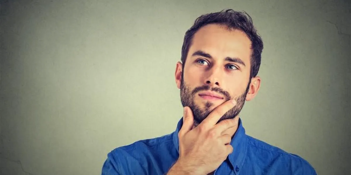 heureux jeune homme pensant rêverie en levant isolé sur fond de mur gris