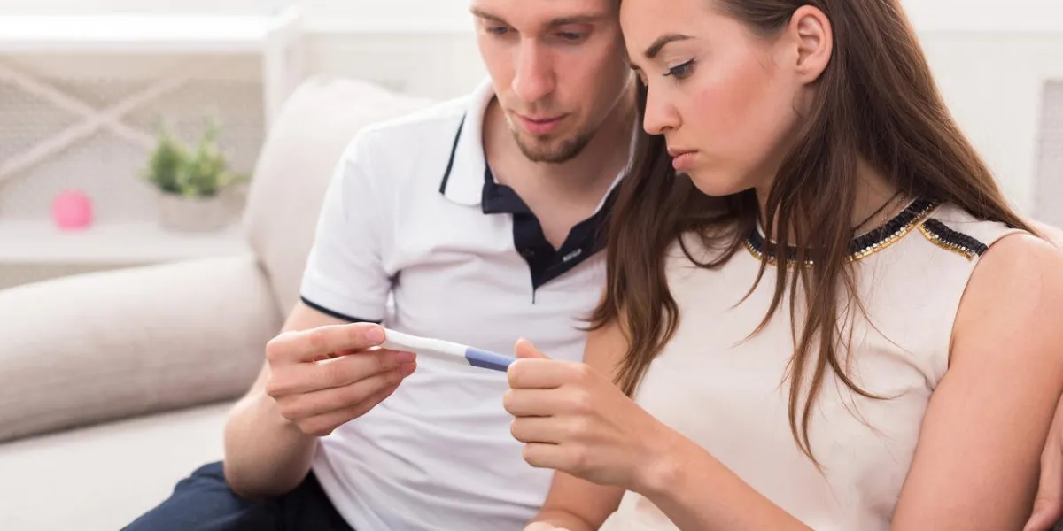 couple triste après le résultat du test de grossesse négatif, assis sur le canapé à la maison, copie espace