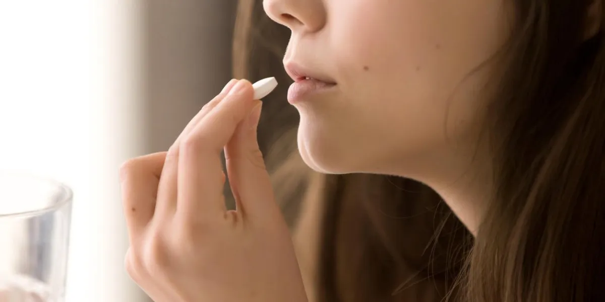 close up image of woman putting white round pill in mouth sick female taking medicines, antidepressant, painkiller or antibiotic young lady drinking contraceptives pharmacy and healthcare concept