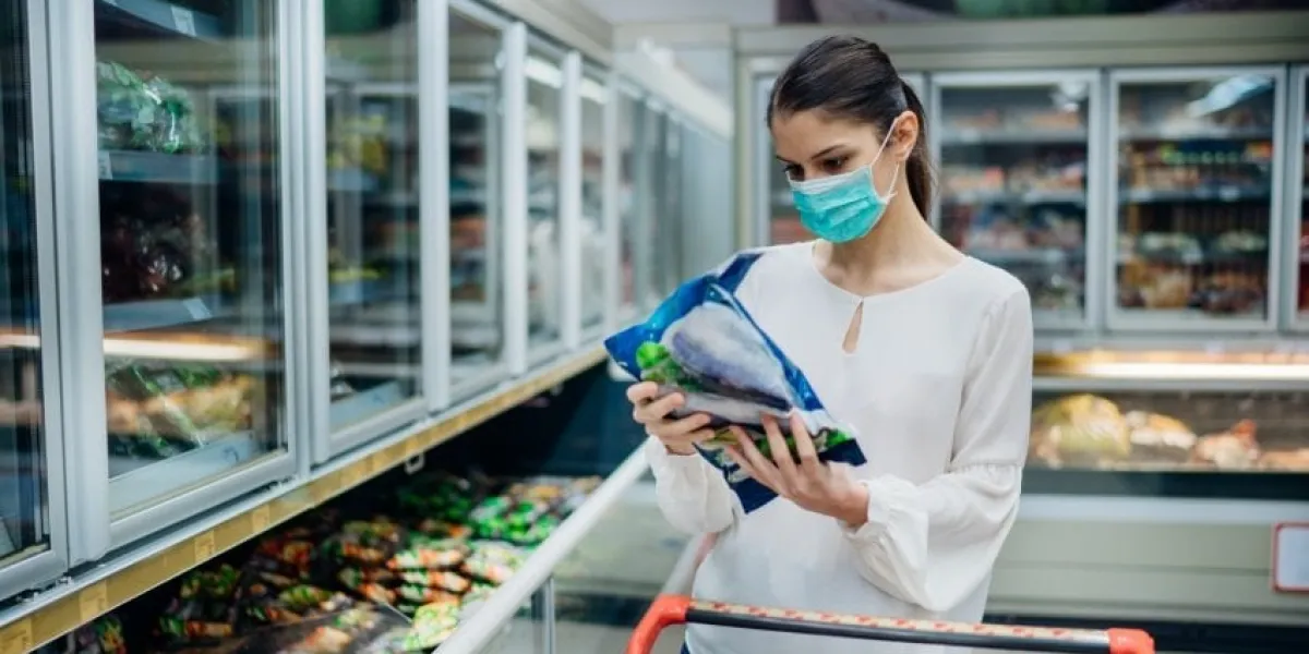 woman with hygienic mask shopping for suppliescpandemic quarantine preparationhoosing nonperishable food essentials from store shelvesbudget buying at a supply storefood supplies shortage