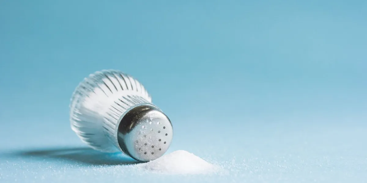 spilled salt and saltshaker on blue background