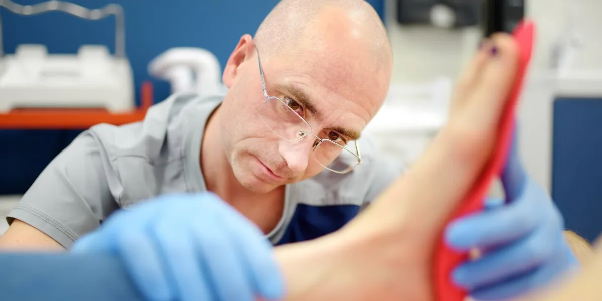 orthopedic insoles fitting orthotic insoles flatfoot treatment podiatry clinic close up image of male orthopedist tries insole on patient's foot in clinic