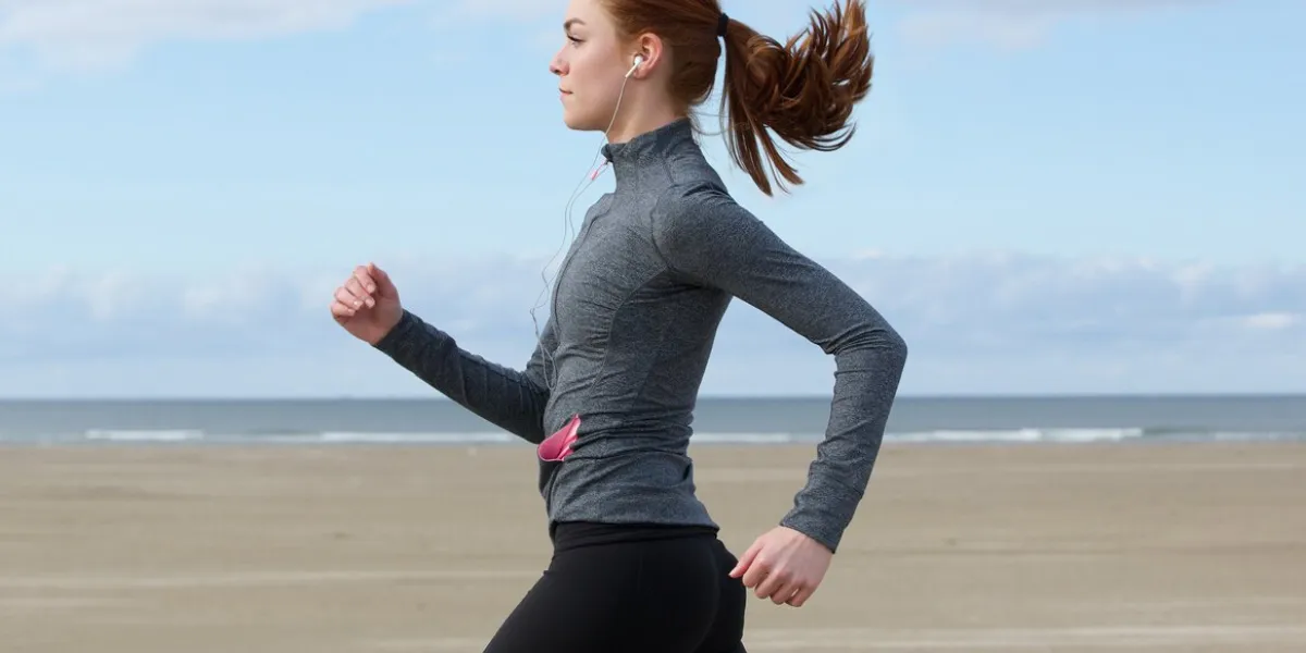 side view portrait of a young woman running by the beach