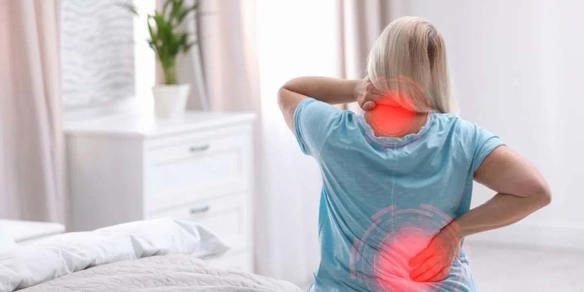 woman suffering from back pain after sleeping on uncomfortable mattress at home